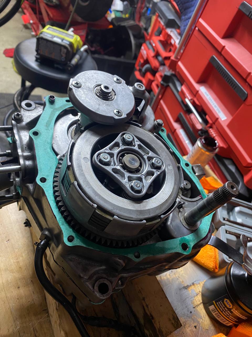 A motorcycle engine opened up on the workbench with the clutch basket and primary drive exposed and a fresh gasket fitted