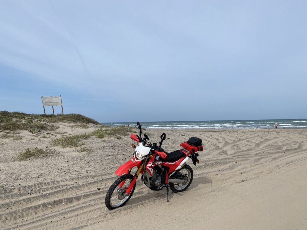 My red Honda CRF 250L parked on the sand at Boca Chica beach in Texas, near the SpaceX launch site