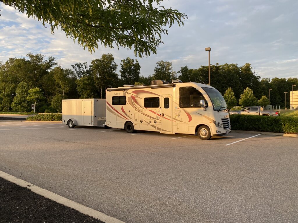 The 2018 Thor Axis Class A motorhome parked at golden hour with a white enclosed cargo trailer hitched behind it