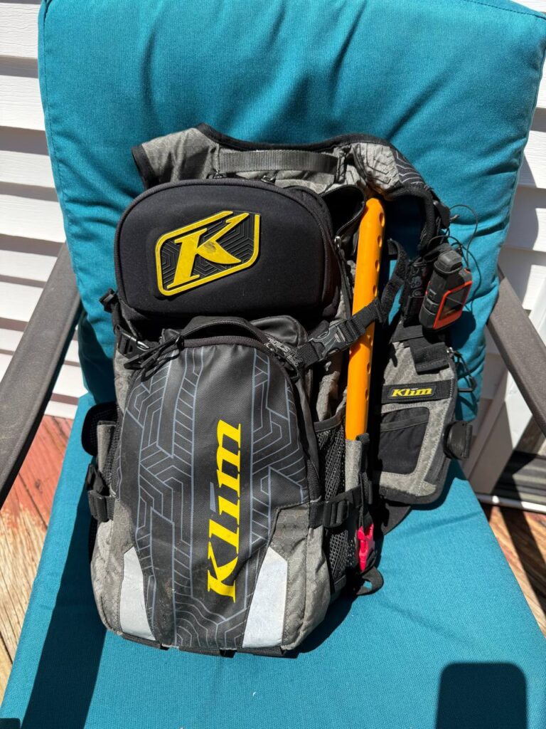 A KLIM Nac Pak technical backpack loaded with gear, a folding saw strapped to the side