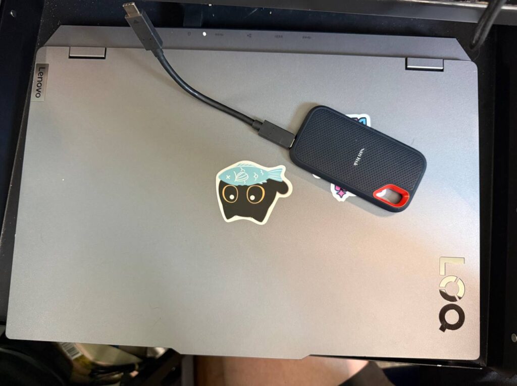 A SanDisk Extreme portable SSD plugged into a Lenovo laptop with a short USB-C cable