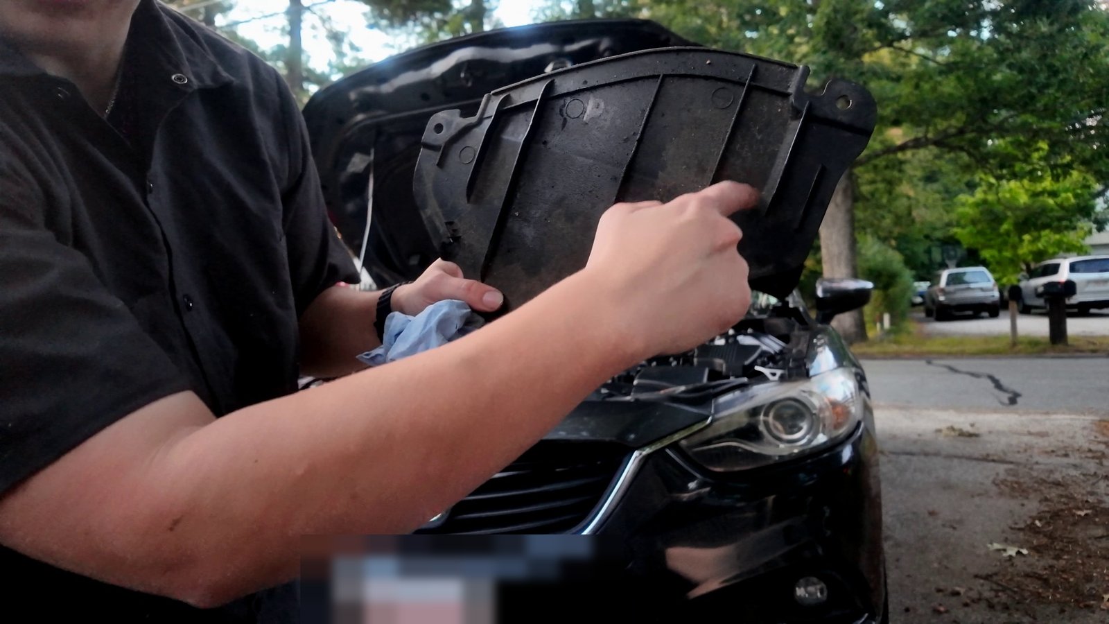 Emily pointing at the shiny oil residue on the Mazda 6 bottom cover