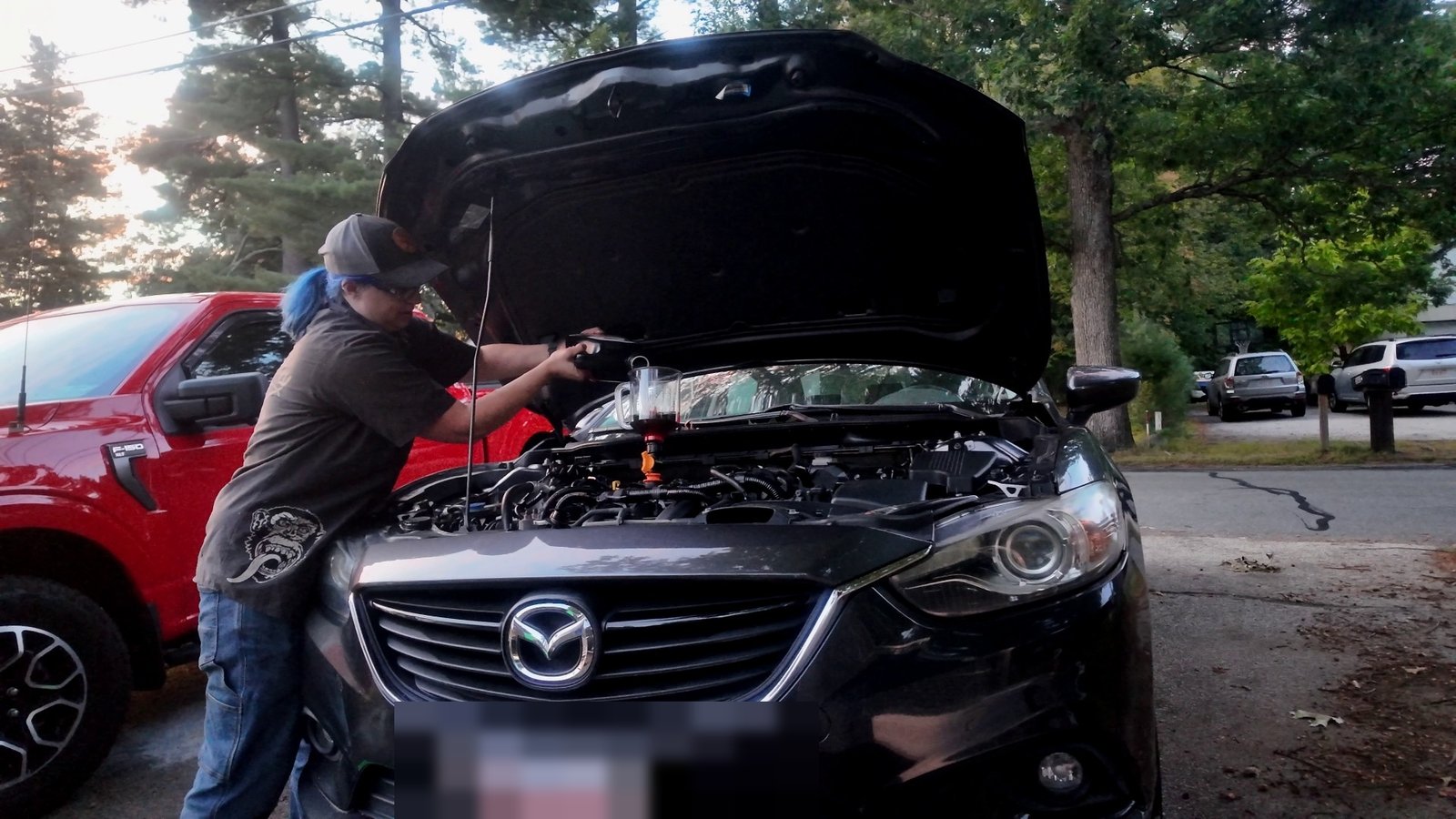 Emily pouring fresh oil into the Mazda 6 engine through a funnel