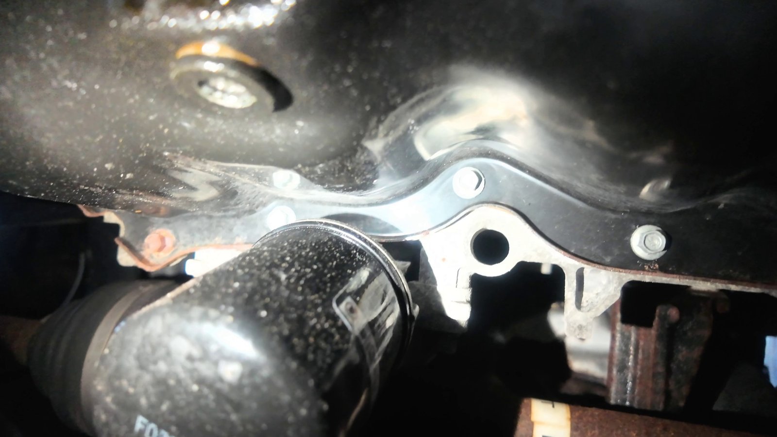 Underside of a Mazda 6 showing the oil filter and the drain plug on the oil pan