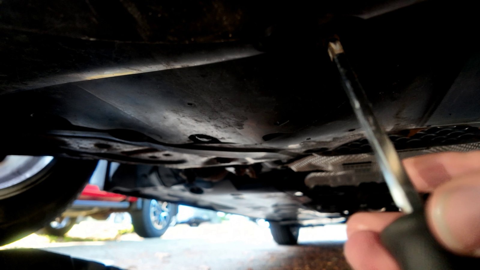 Flathead screwdriver on the Mazda 3 undertray cover that covers the drain plug and oil filter